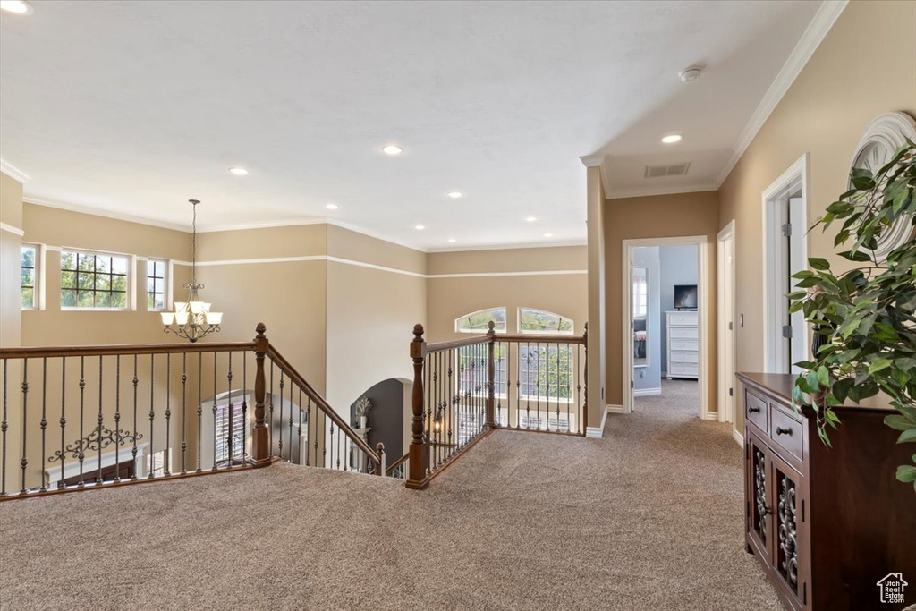 Corridor with visible vents, carpet floors, an upstairs landing, an inviting chandelier, and ornamental molding