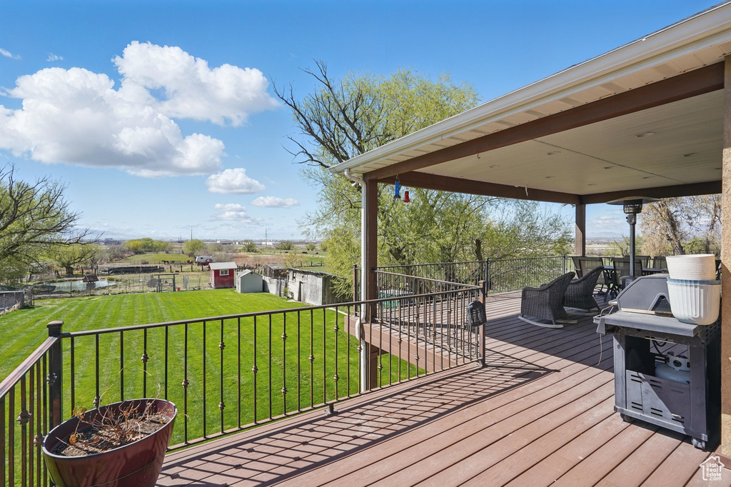 Wooden terrace featuring a lawn, an outbuilding, and a water view