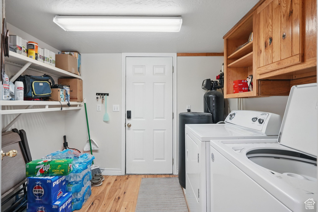 Laundry area featuring light wood-style floors, cabinet space, and washing machine and clothes dryer