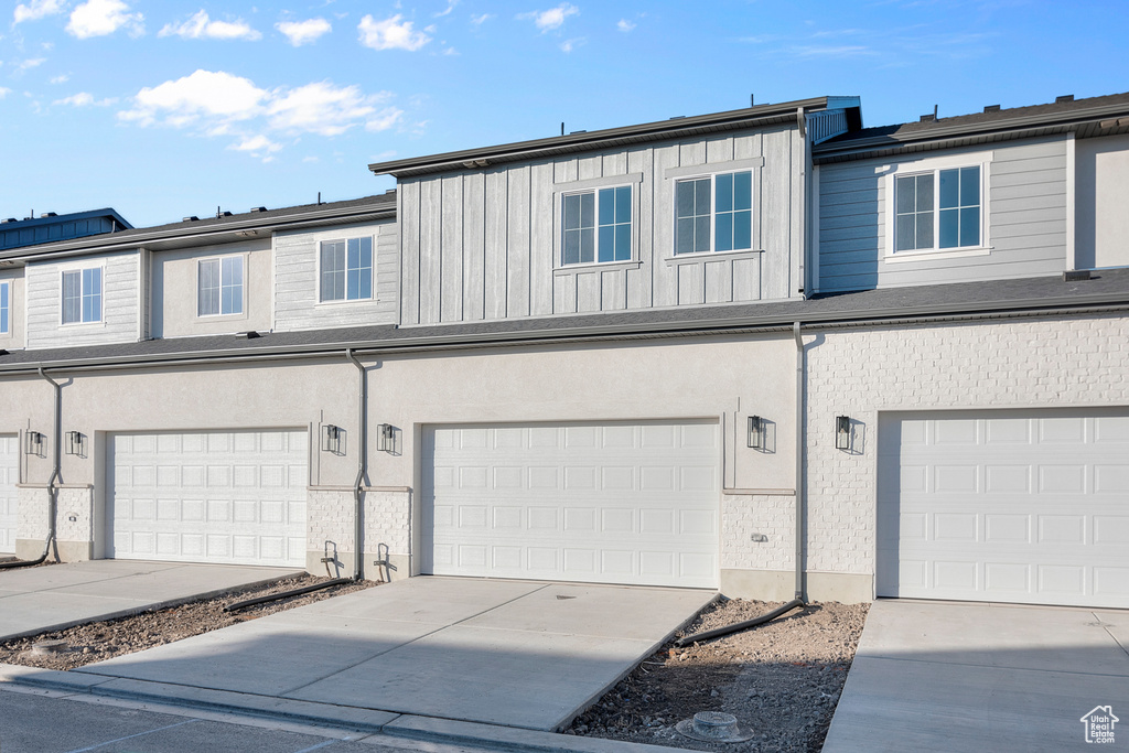 View of property with board and batten siding, driveway, and a garage