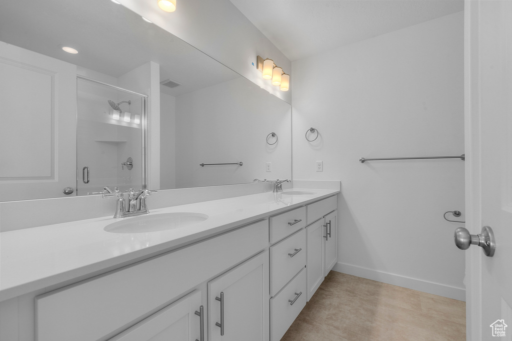 Full bath featuring a sink, a shower with door, double vanity, and visible vents