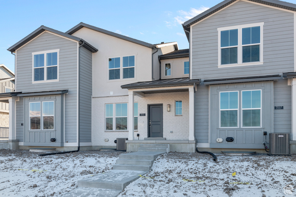 View of front of house featuring a standing seam roof and central AC