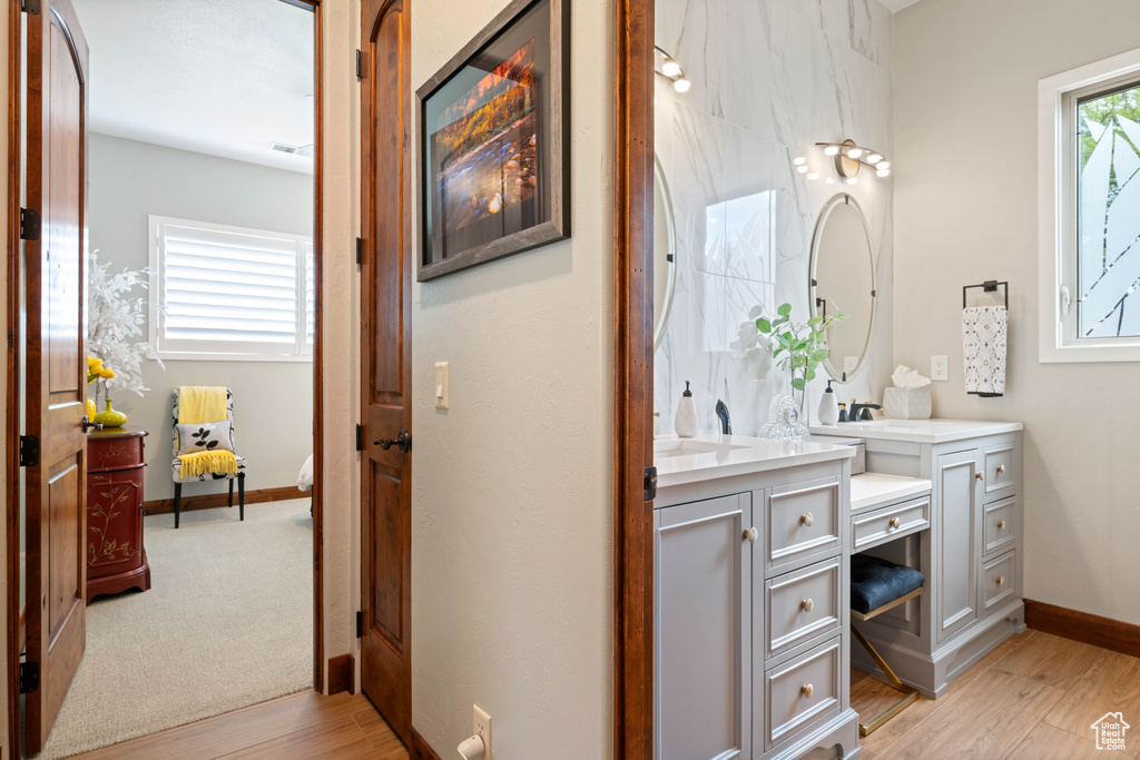 Bathroom with vanity, baseboards, wood finished floors, and visible vents