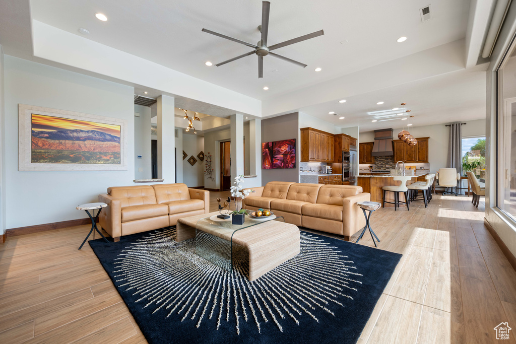 Living room featuring baseboards, ceiling fan with notable chandelier, light wood-style flooring, and visible vents