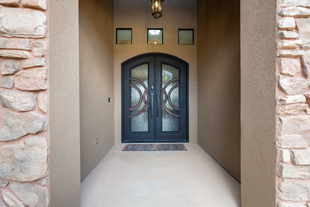 View of exterior entry with french doors, stucco siding, and stone siding