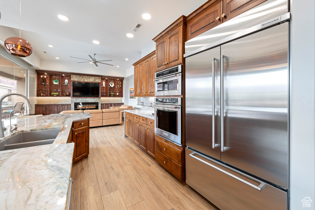 Kitchen with ceiling fan, visible vents, light stone countertops, open floor plan, and stainless steel appliances