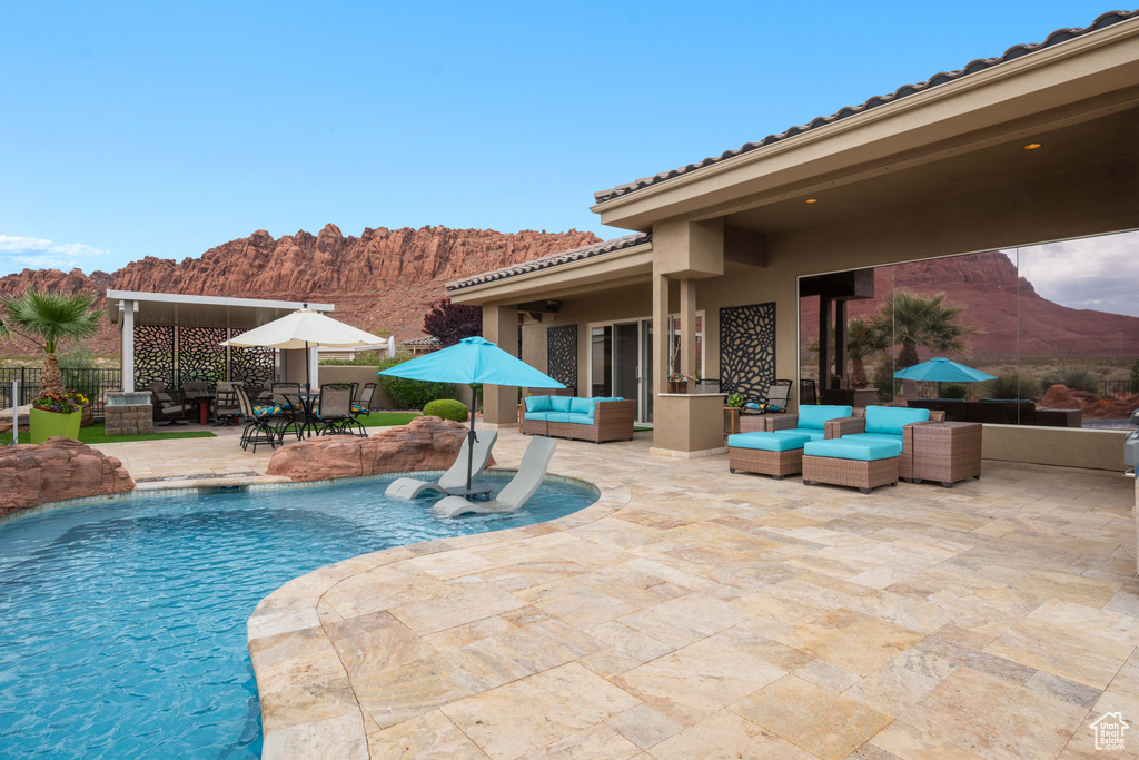 View of swimming pool featuring fence, an outdoor hangout area, a fenced in pool, a mountain view, and a patio
