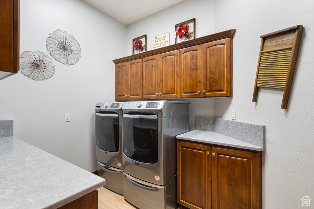 Laundry area featuring cabinet space, independent washer and dryer, and light wood finished floors