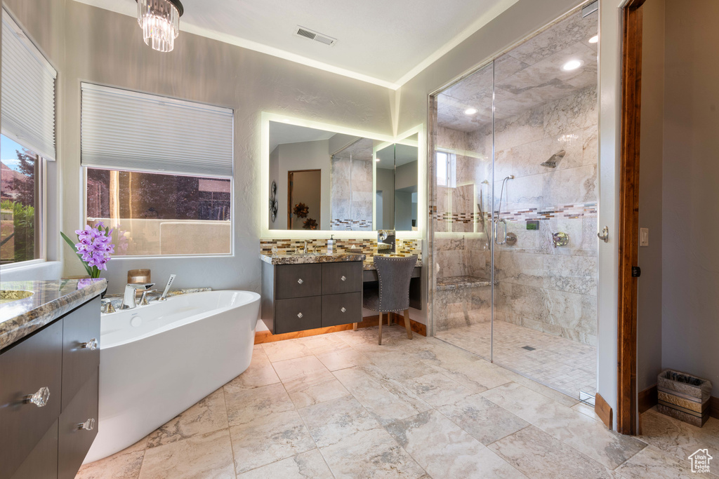 Bathroom with a freestanding tub, vanity, tiled shower, and visible vents