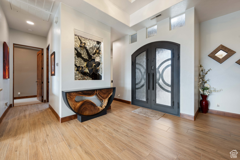 Foyer entrance featuring french doors, baseboards, and light wood-style floors