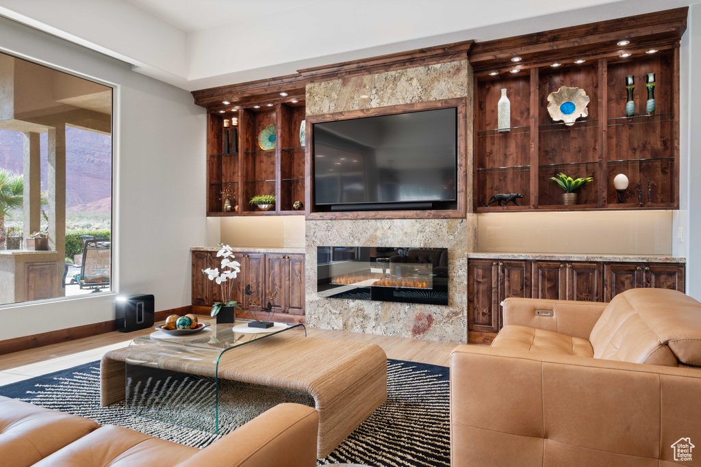 Living room with a glass covered fireplace, baseboards, and wood finished floors