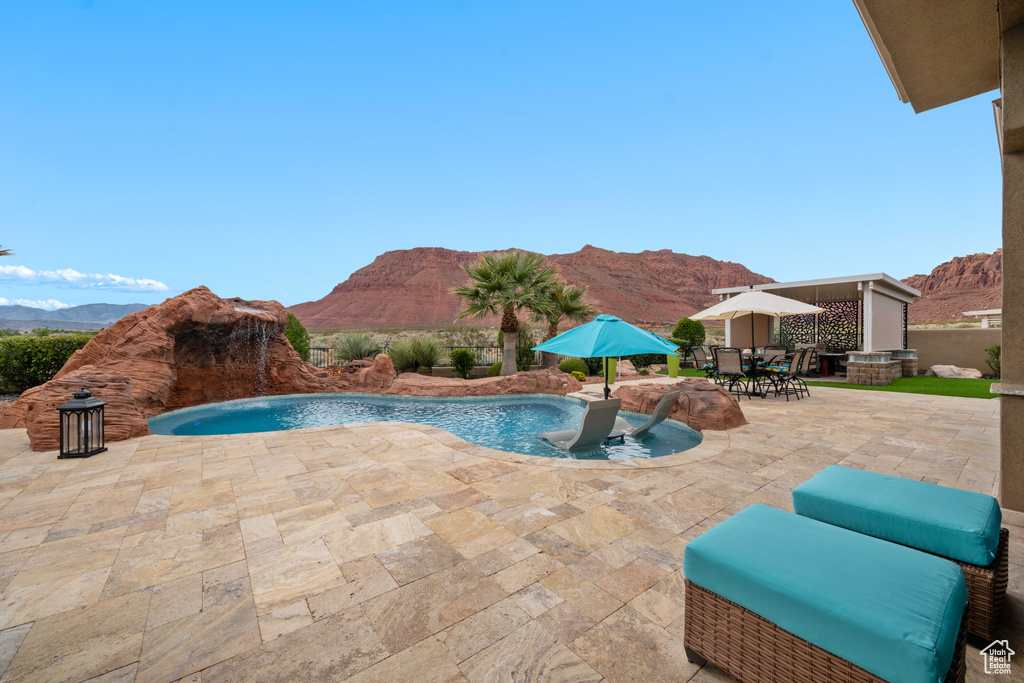 View of pool with a patio, a fenced in pool, outdoor dining area, and a mountain view