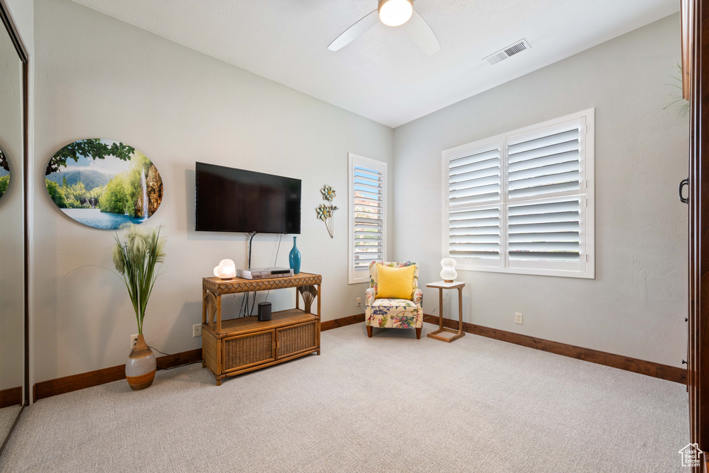 Living area featuring carpet floors, ceiling fan, visible vents, and baseboards