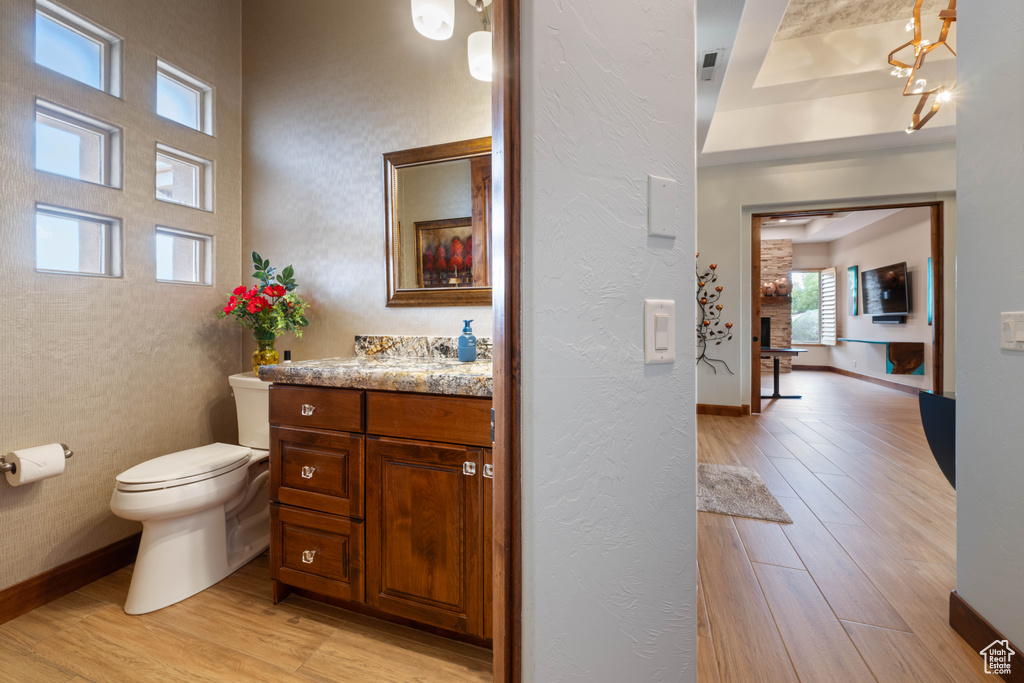 Half bathroom featuring baseboards, vanity, toilet, and wood finished floors