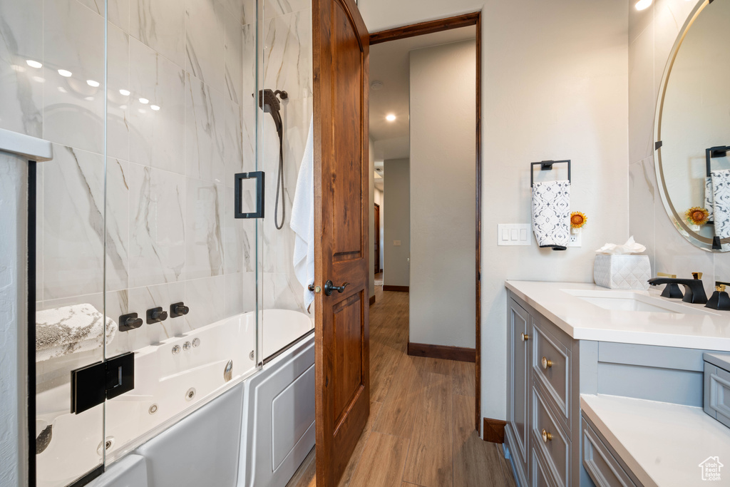 Bathroom with bath / shower combo with glass door, baseboards, vanity, and wood finished floors