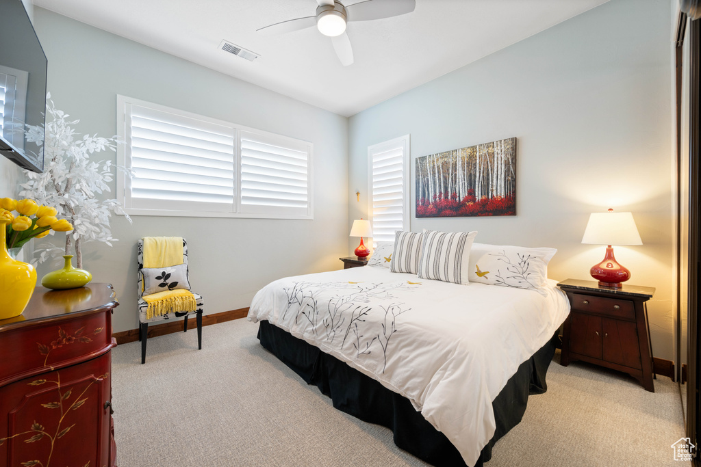 Bedroom with baseboards, light carpet, a ceiling fan, and visible vents