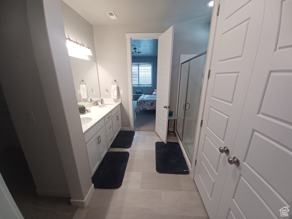 Bathroom featuring ensuite bath, a shower stall, double vanity, and baseboards