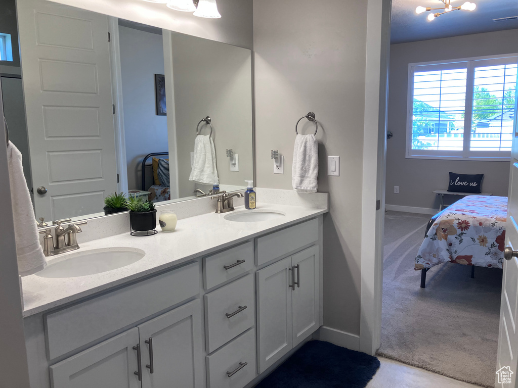 Ensuite bathroom featuring double vanity and baseboards