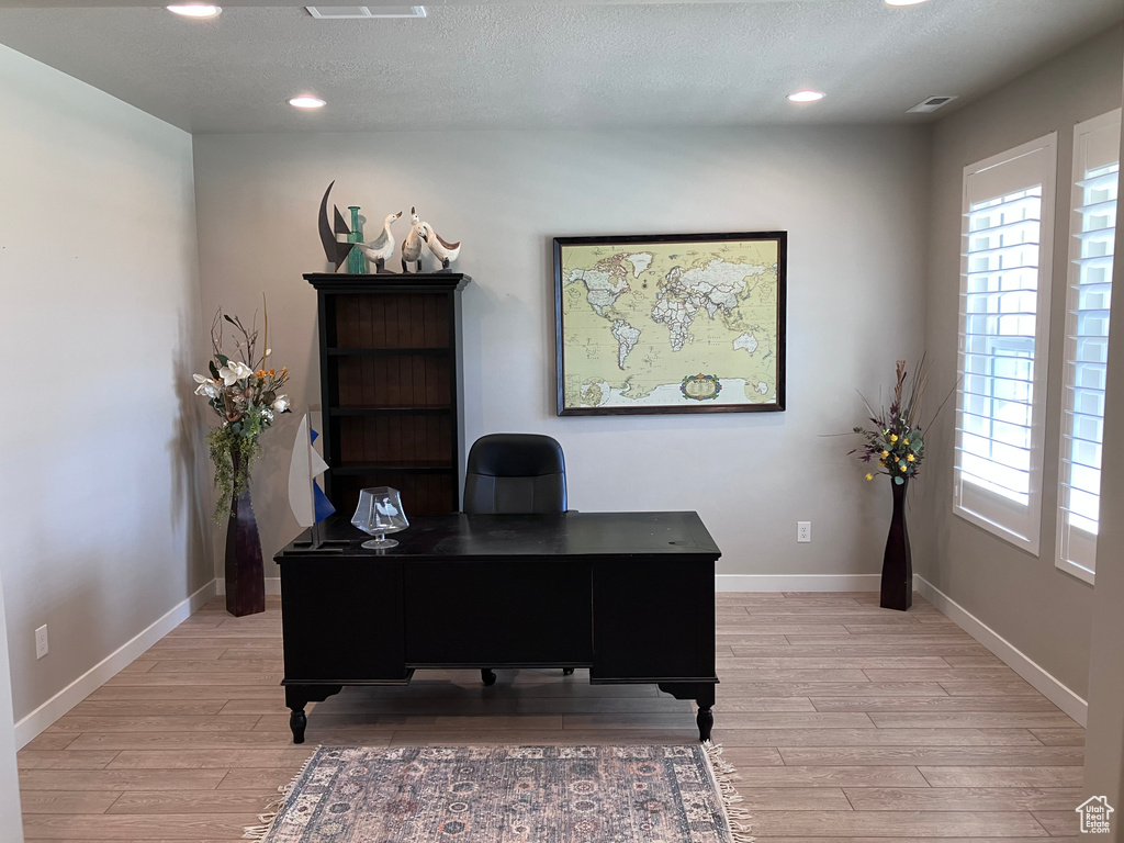 Office featuring light wood-style floors, baseboards, recessed lighting, and a textured ceiling