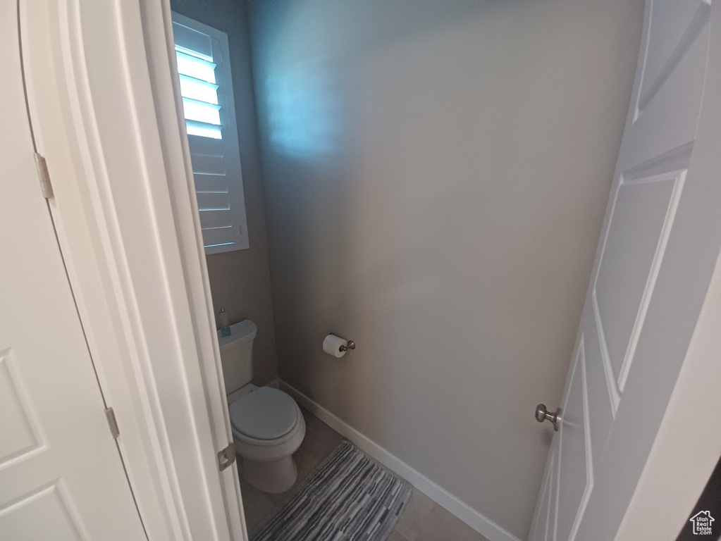 Bathroom featuring toilet, baseboards, and tile patterned flooring