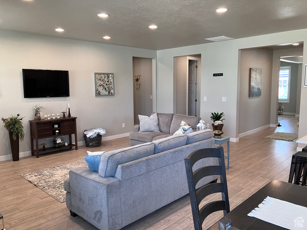Living room with recessed lighting, light wood-style floors, and a textured ceiling