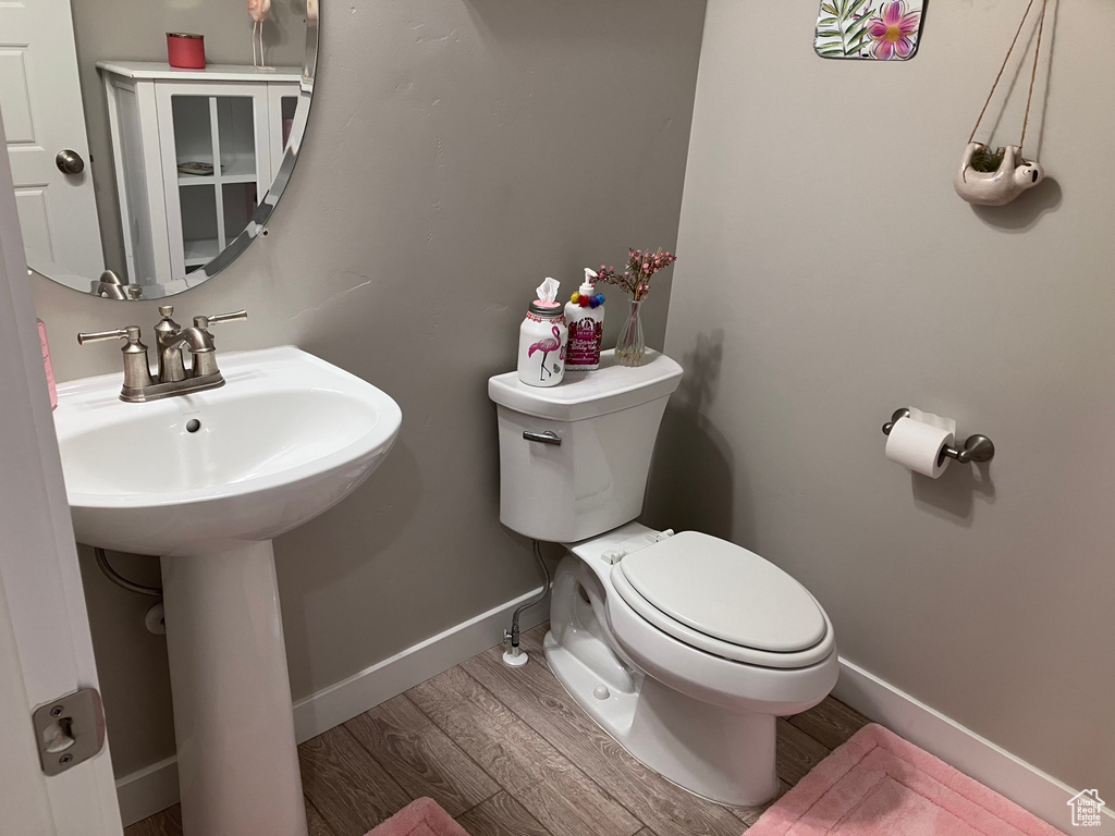 Half bath with wood finished floors and toilet