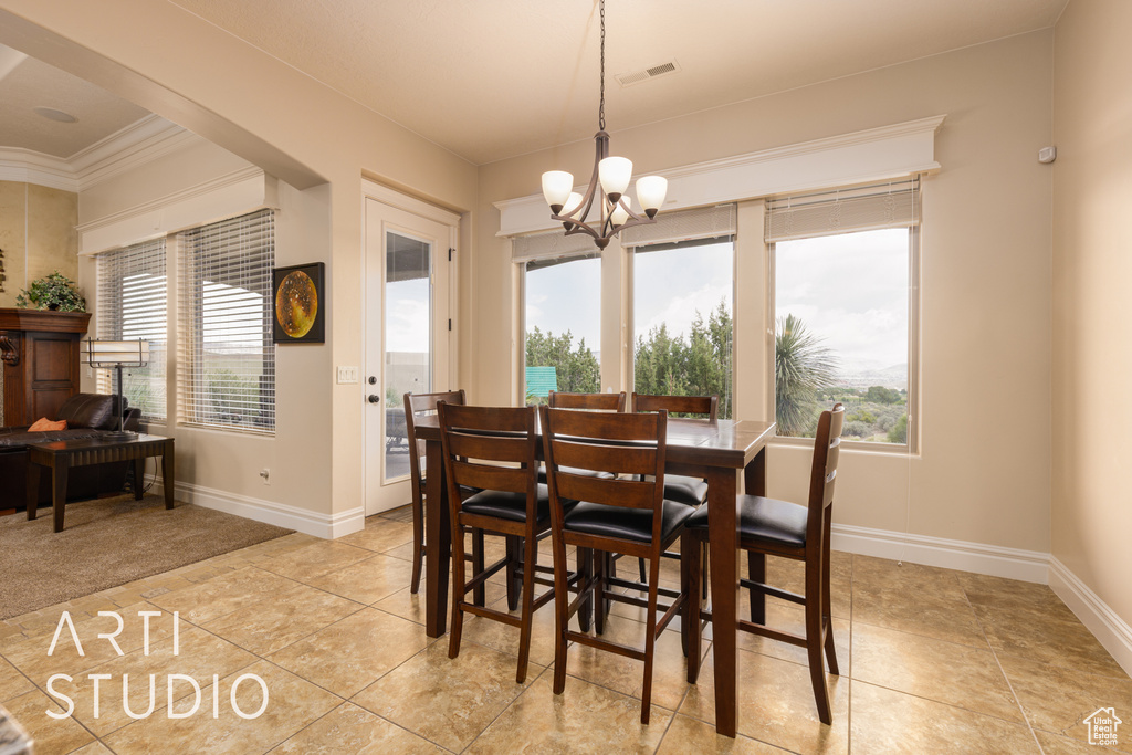 Dining room featuring crown molding, a chandelier, plenty of natural light, and visible vents