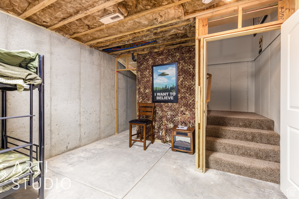 Unfinished basement featuring stairs and visible vents