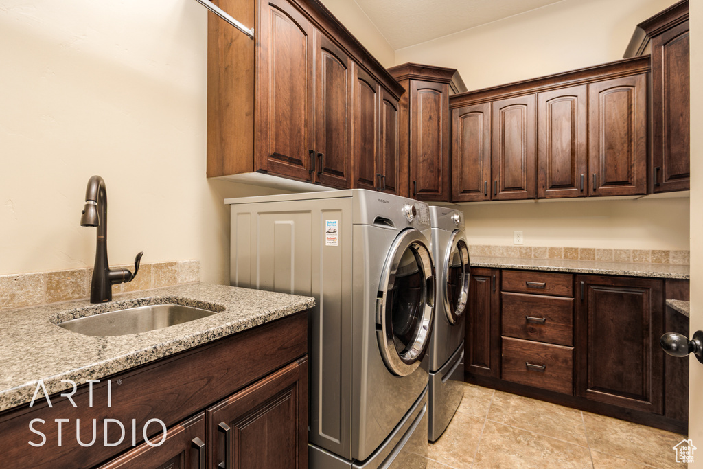 Washroom featuring a sink, cabinet space, and independent washer and dryer