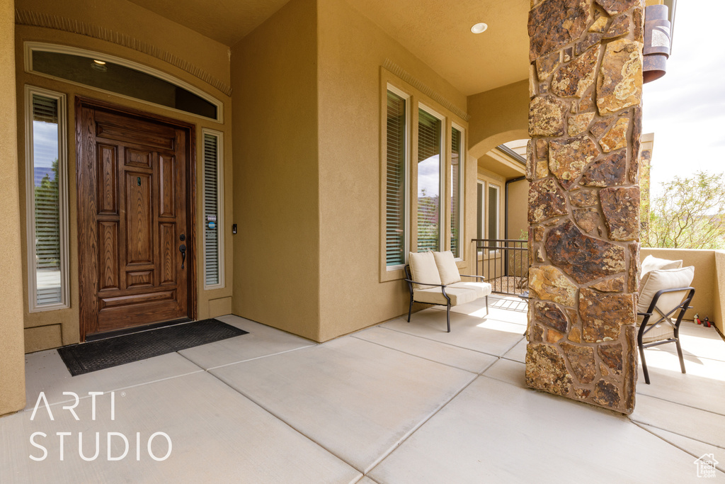 View of exterior entry with covered porch, stone siding, and stucco siding