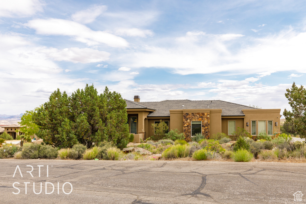 Southwest-style home featuring a chimney, stone siding, and stucco siding