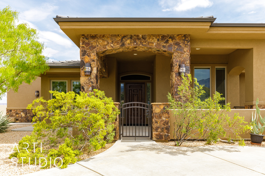 Property entrance featuring fence, stone siding, and stucco siding