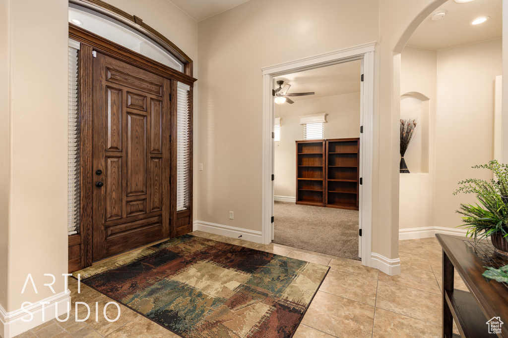 Tiled entryway with baseboards, arched walkways, and ceiling fan
