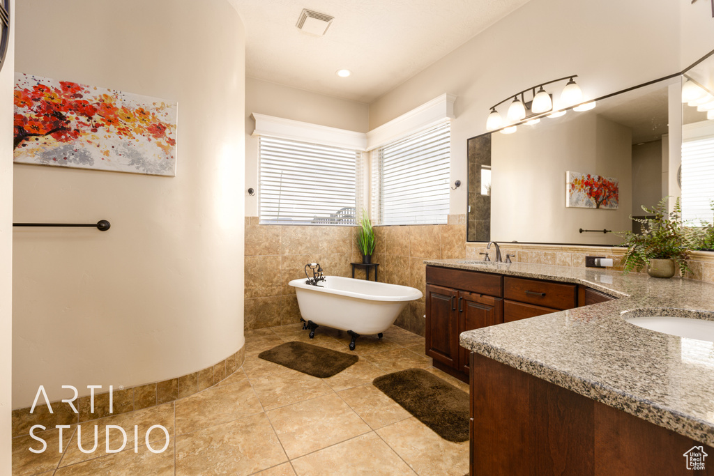 Bathroom featuring visible vents, tile patterned floors, two vanities, a soaking tub, and a sink