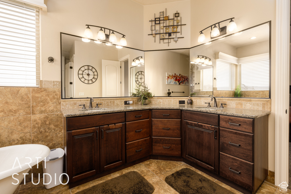 Full bathroom featuring a sink, a wealth of natural light, and tile walls