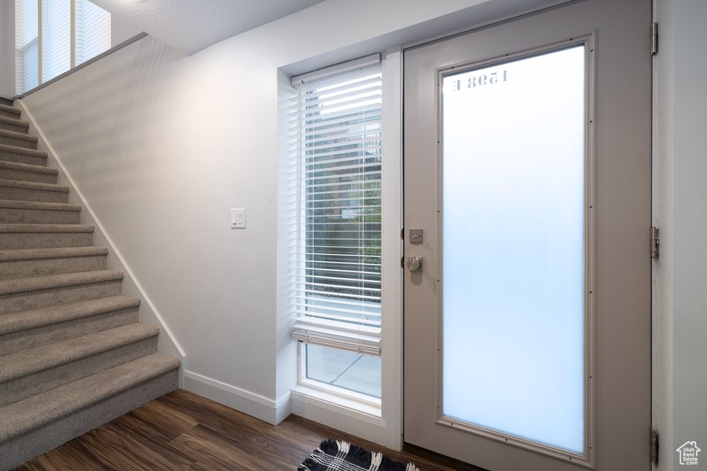 Doorway featuring stairs, baseboards, and dark wood-style floors
