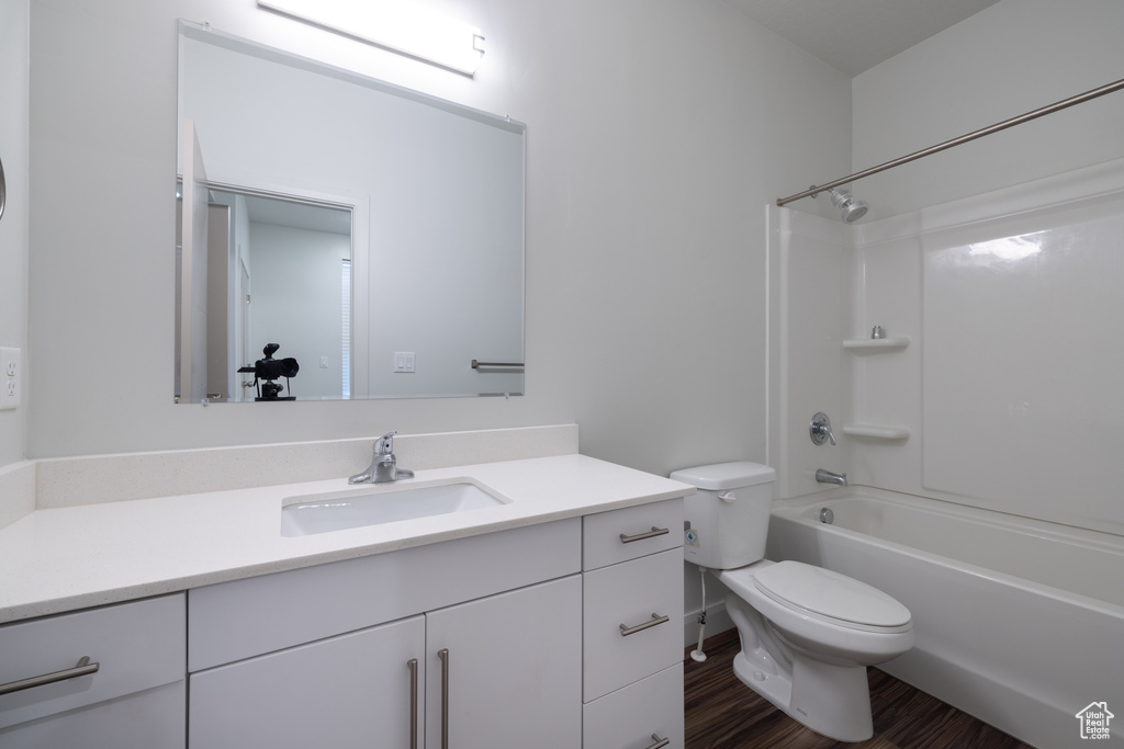 Full bath with toilet, bathing tub / shower combination, wood finished floors, and vanity