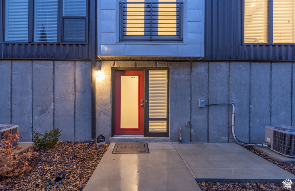 Property entrance featuring board and batten siding and cooling unit