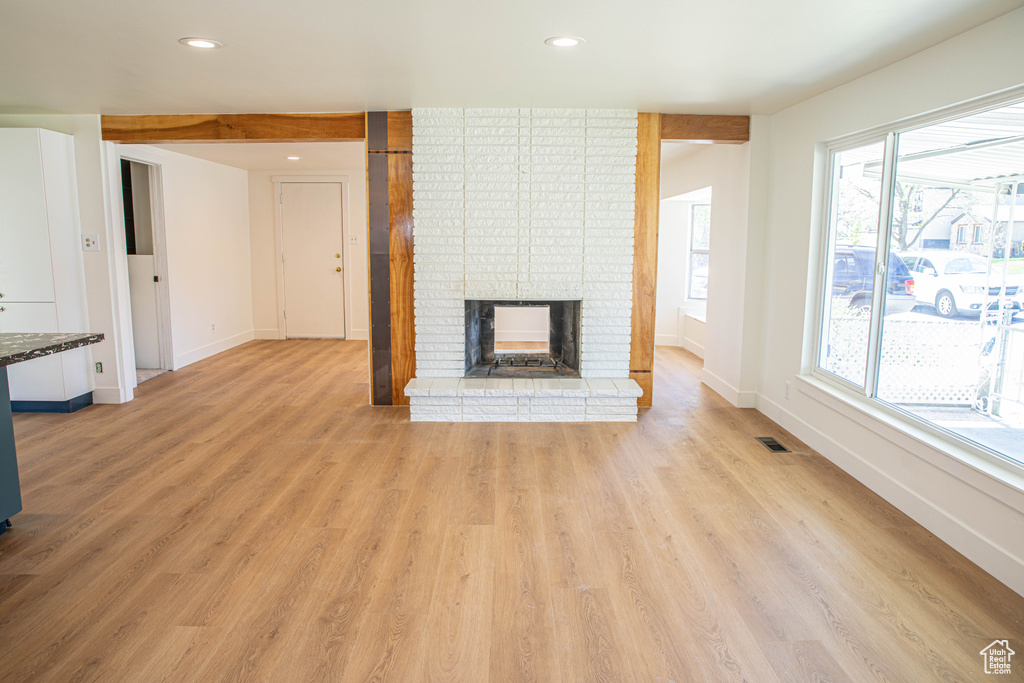 Unfurnished living room featuring visible vents, a brick fireplace, baseboards, light wood-style floors, and recessed lighting