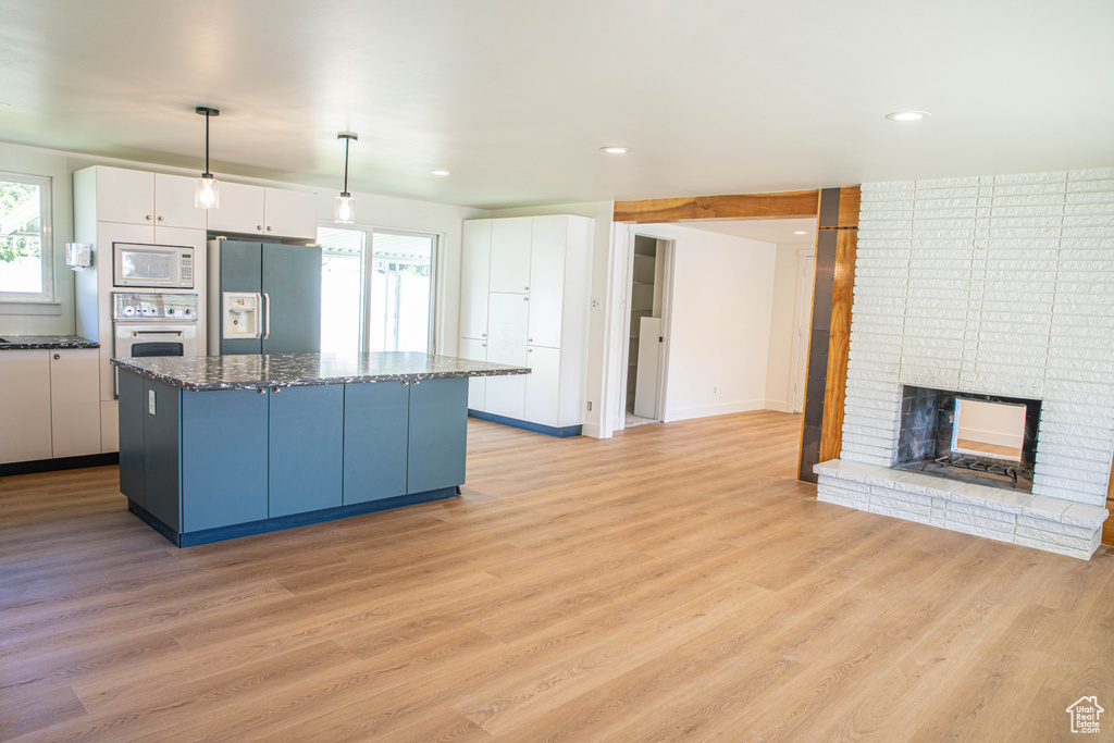 Kitchen with a center island, plenty of natural light, white appliances, and white cabinetry