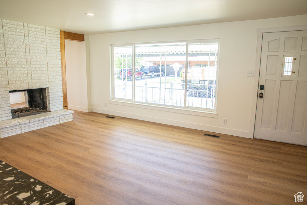 Unfurnished living room with baseboards, wood finished floors, and visible vents