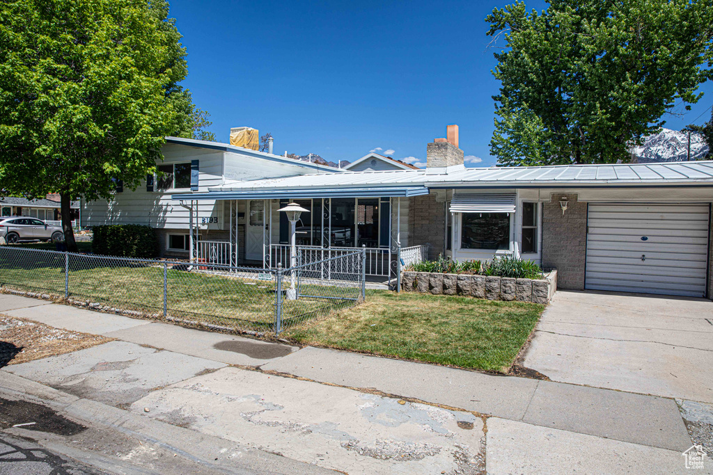 Tri-level home with a fenced front yard, a chimney, a front yard, and a garage