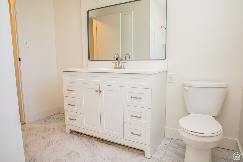 Bathroom featuring baseboards, vanity, toilet, and marble finish floor