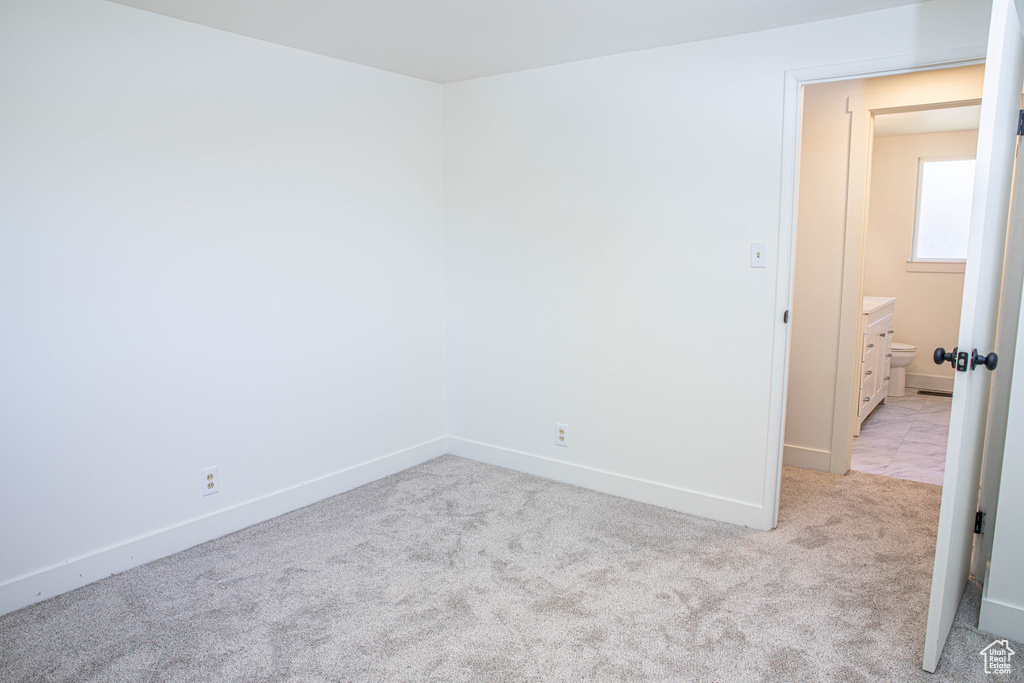 Empty room with baseboards and light colored carpet