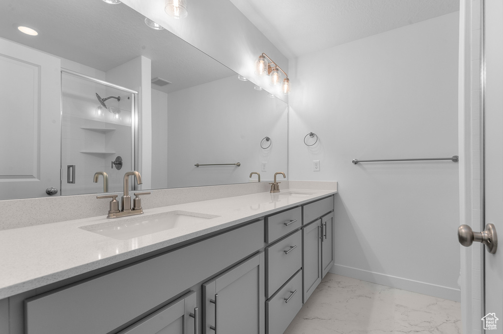 Full bathroom featuring double vanity, a sink, marble finish floor, and a stall shower