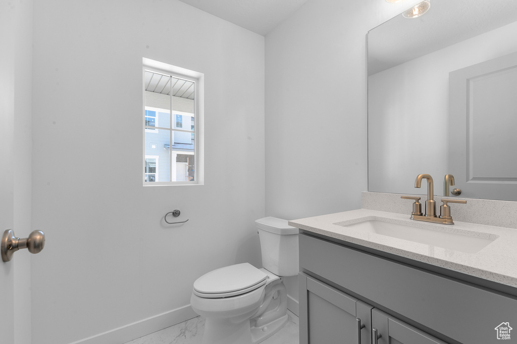 Bathroom featuring baseboards, marble finish floor, toilet, and vanity