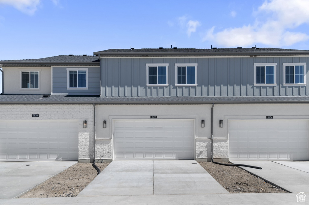 Townhome / multi-family property with an attached garage, board and batten siding, and driveway