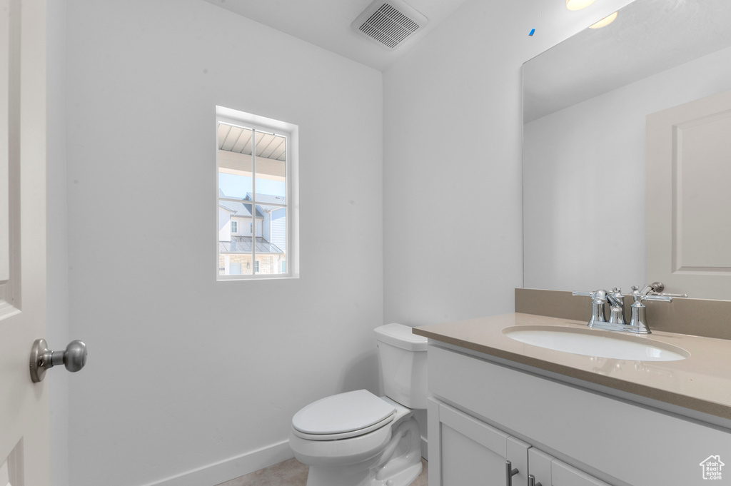 Half bath featuring toilet, visible vents, and vanity