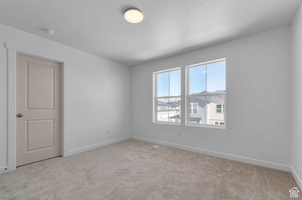 Unfurnished room with carpet floors, baseboards, and visible vents