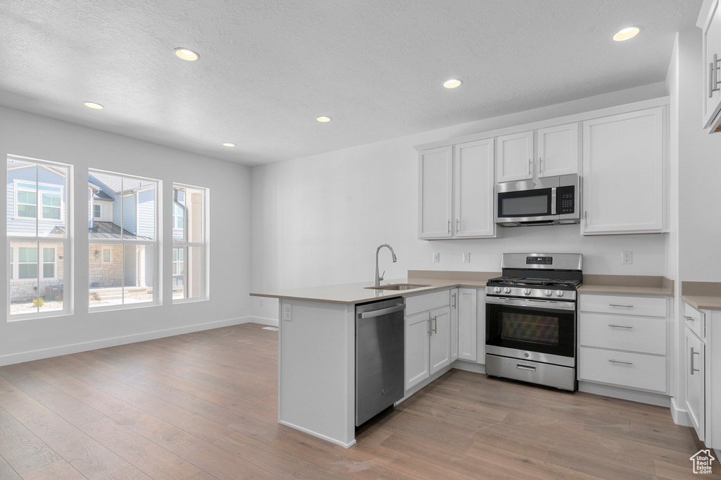 Kitchen with white cabinets, stainless steel appliances, a sink, and a peninsula